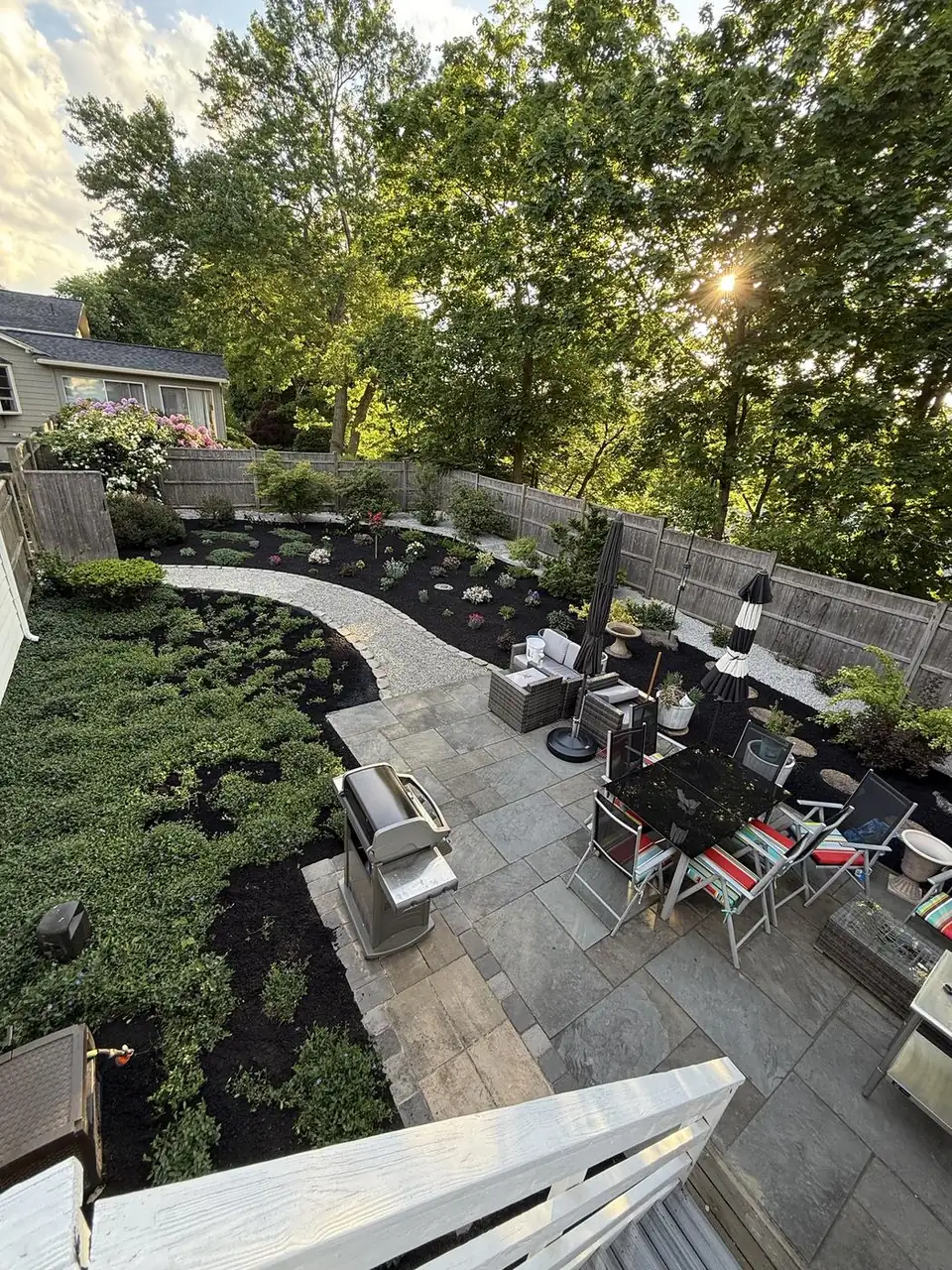 Backyard beds with fresh mulch and new plantings, seen from the deck