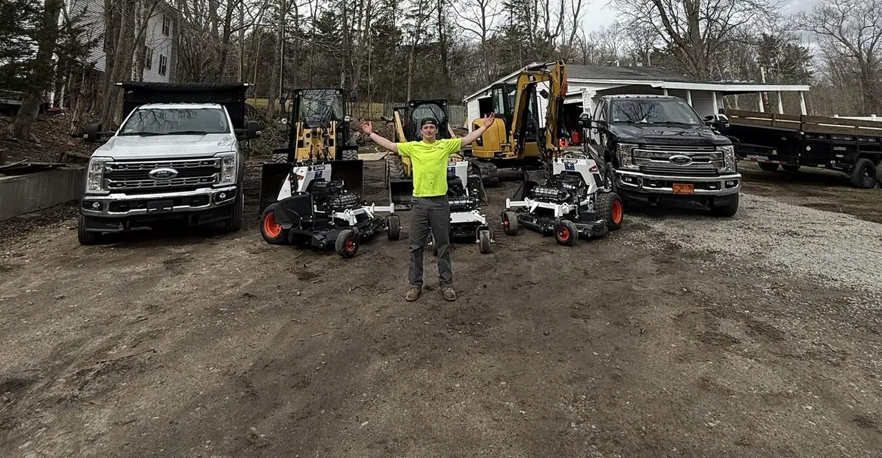 John A. DeMarco standing in front of the company trucks, mowers, loader, skid steer and excavator
